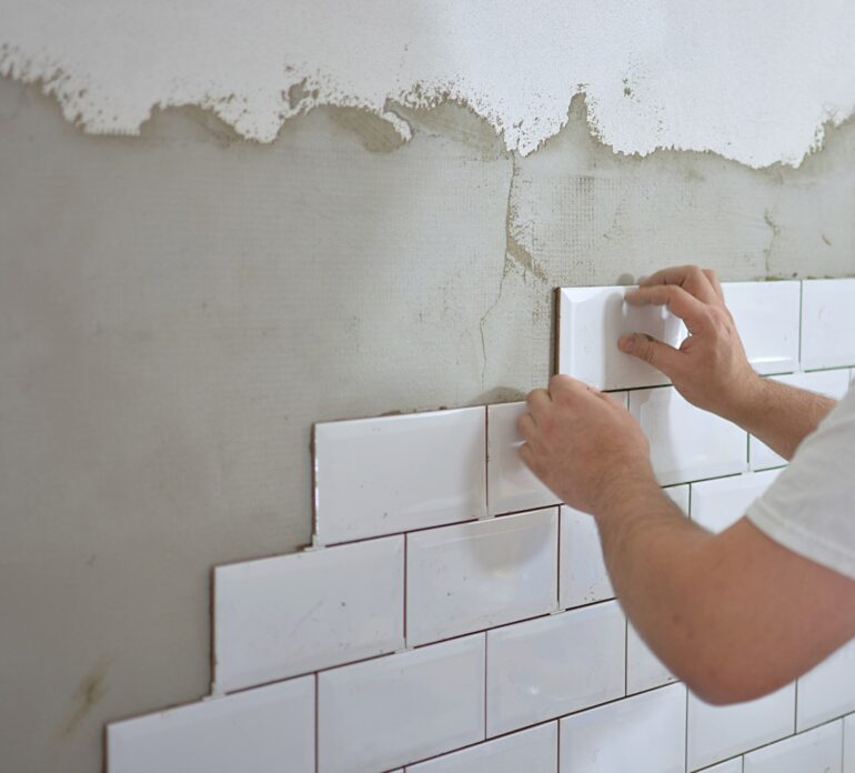 man tiling a bathroom wall