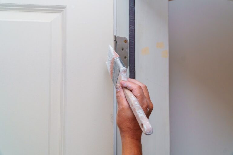 man painting a door white